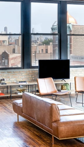 Leather sofa loft with exposed brick wall and Chicago skyline through floor-to-ceiling windows